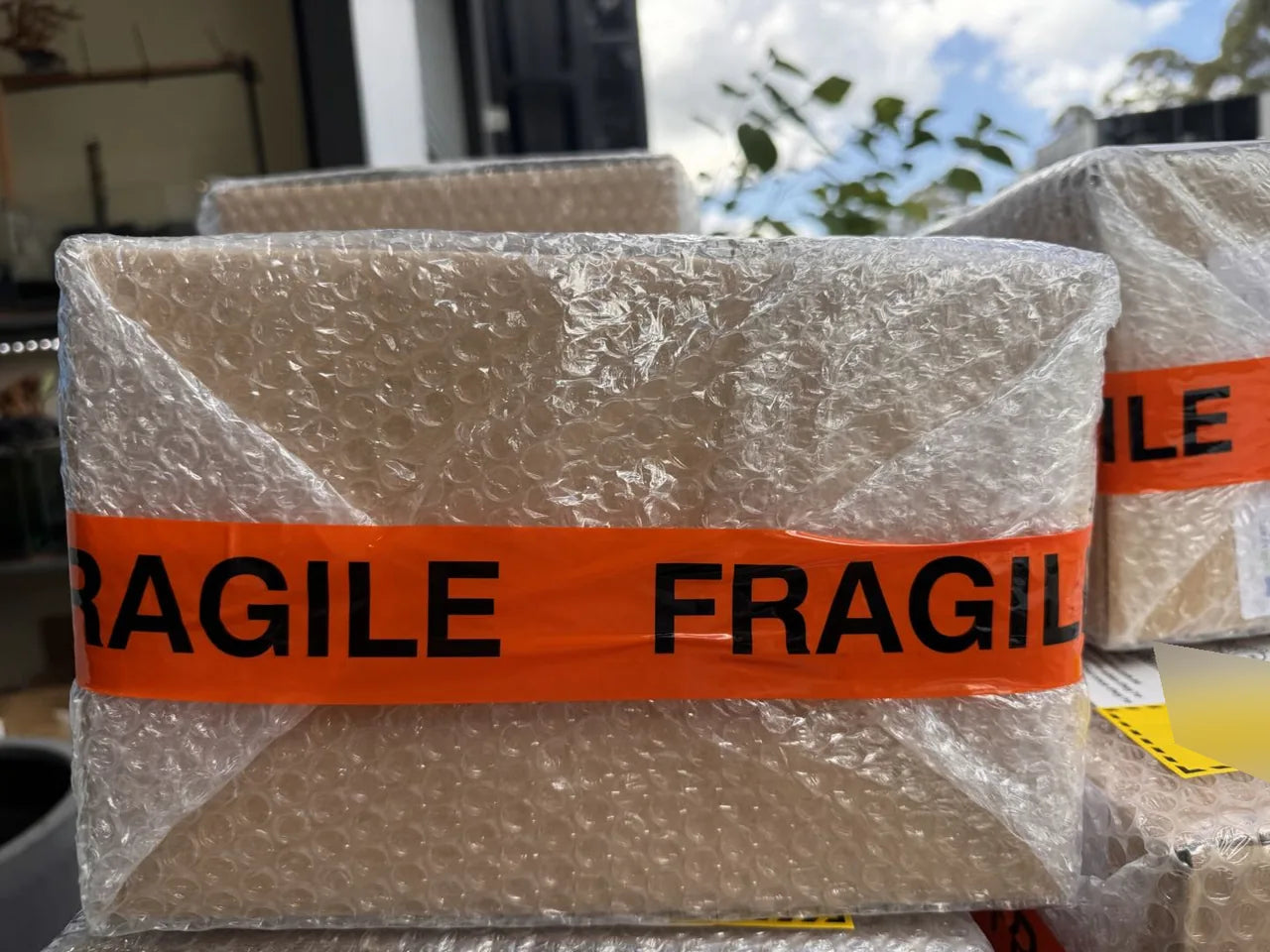 A shipping carton wrapped in an outer layer of bubble wrap and secured with FRAGILE tape